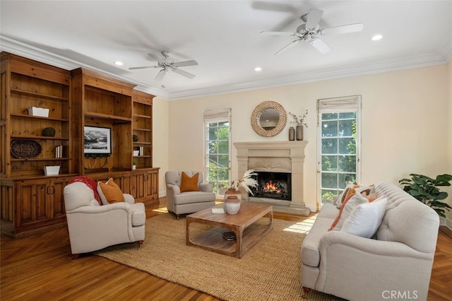 living area featuring crown molding, a premium fireplace, ceiling fan, and a wealth of natural light