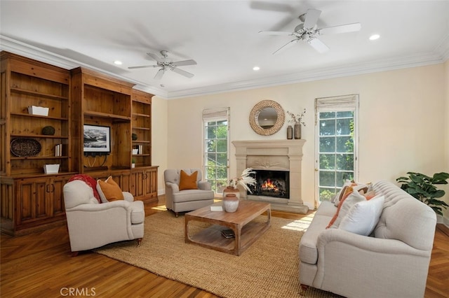 living room featuring crown molding, a premium fireplace, a ceiling fan, and a healthy amount of sunlight