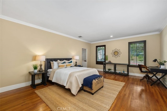 bedroom with crown molding, wood finished floors, visible vents, and baseboards