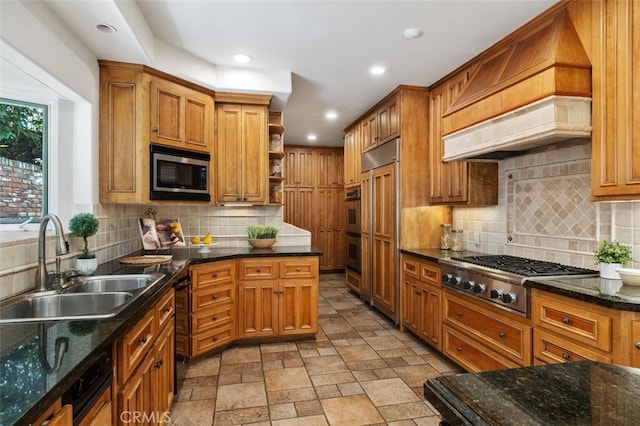 kitchen featuring open shelves, stone tile flooring, brown cabinetry, a sink, and built in appliances