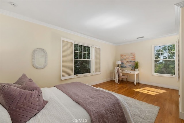 bedroom featuring baseboards, visible vents, ornamental molding, and wood finished floors