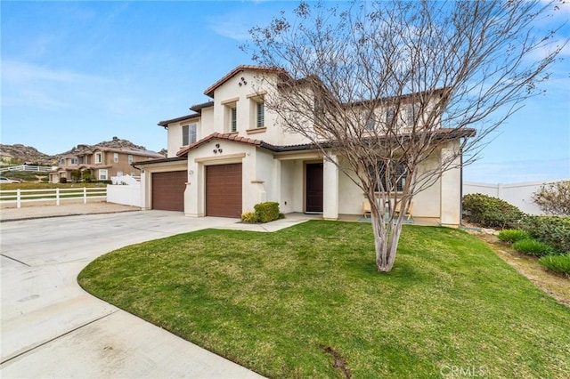 mediterranean / spanish house featuring stucco siding, an attached garage, fence, driveway, and a front lawn