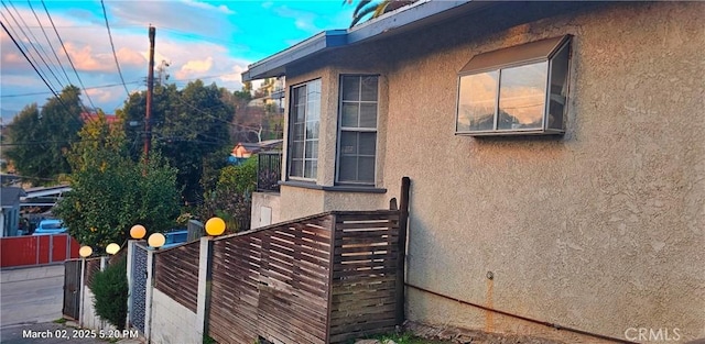 view of side of property with fence and stucco siding