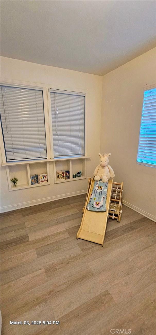 recreation room featuring baseboards and wood finished floors