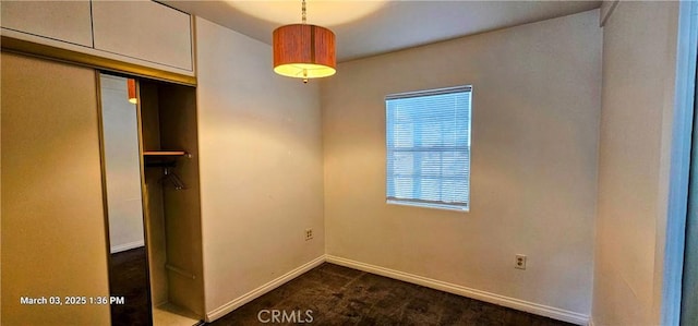 interior space featuring baseboards, dark carpet, and a closet