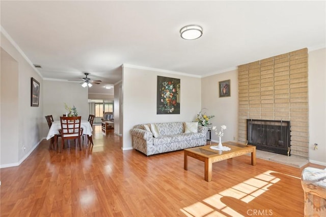 living room featuring light wood-type flooring, a brick fireplace, and ornamental molding