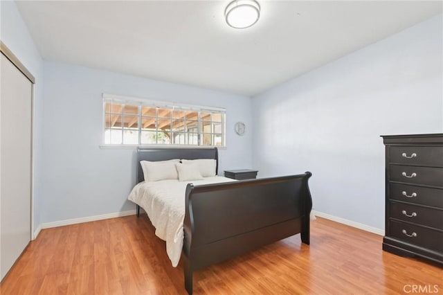 bedroom featuring light wood-style floors, a closet, and baseboards