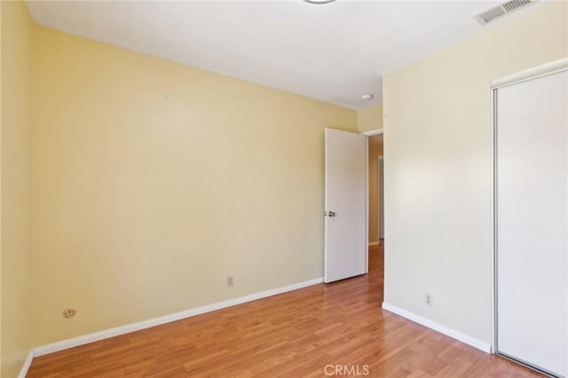 unfurnished bedroom with light wood-style flooring, baseboards, visible vents, and a closet