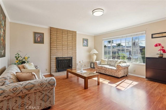 living room with a brick fireplace, crown molding, baseboards, and wood finished floors