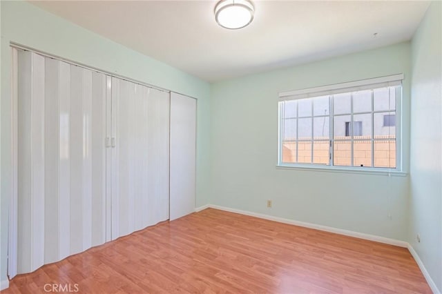 unfurnished bedroom with a closet, baseboards, and wood finished floors