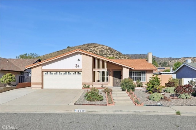 view of front of house featuring stucco siding, driveway, a mountain view, an attached garage, and a chimney