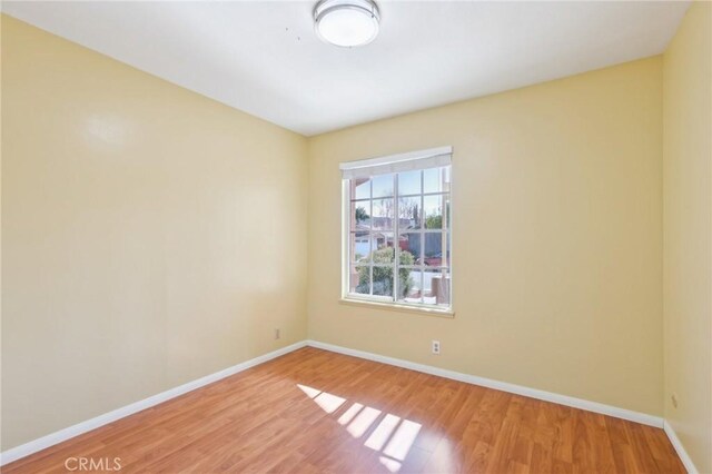spare room with baseboards and light wood finished floors