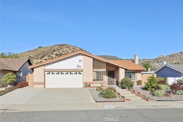 view of front of house with fence, concrete driveway, stucco siding, a chimney, and a garage