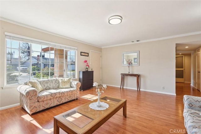 living room with visible vents, ornamental molding, and light wood finished floors