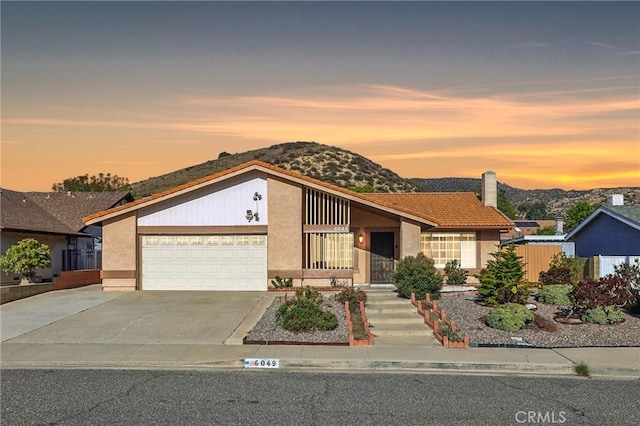 mid-century modern home featuring a mountain view, concrete driveway, an attached garage, and stucco siding