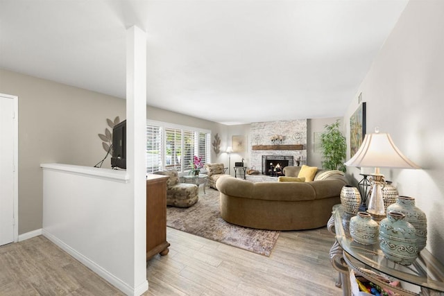 living area featuring a fireplace, baseboards, and wood finished floors