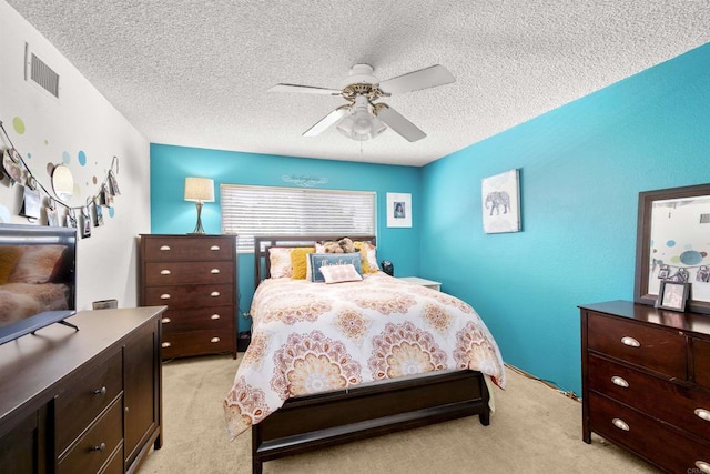 bedroom with light carpet, visible vents, a textured ceiling, and a ceiling fan