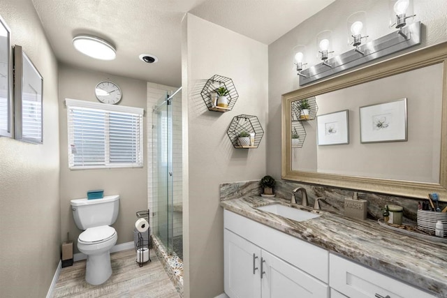 bathroom with a stall shower, toilet, vanity, and wood finished floors