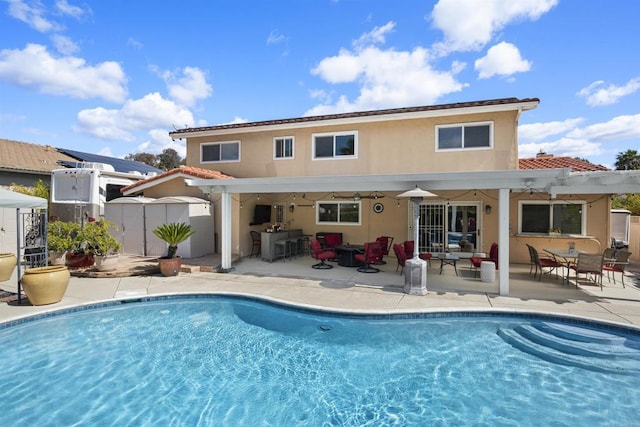 rear view of property featuring a patio, an outdoor pool, a pergola, and stucco siding