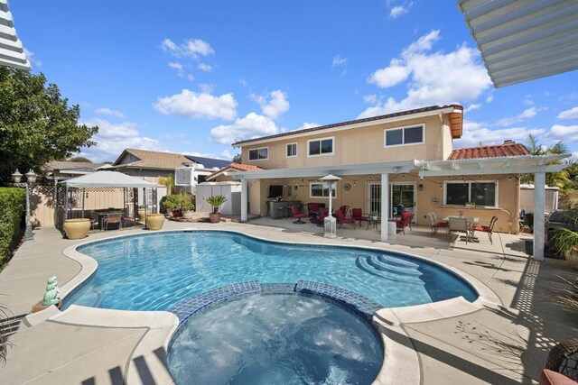 view of pool with a gazebo, a patio area, fence, and a pool with connected hot tub