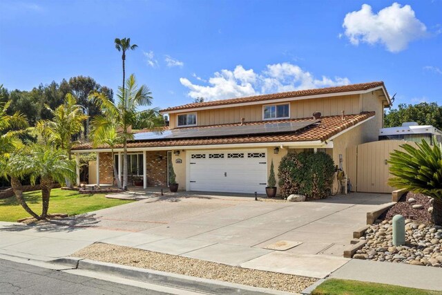 view of front of property with a garage, roof mounted solar panels, driveway, and a gate