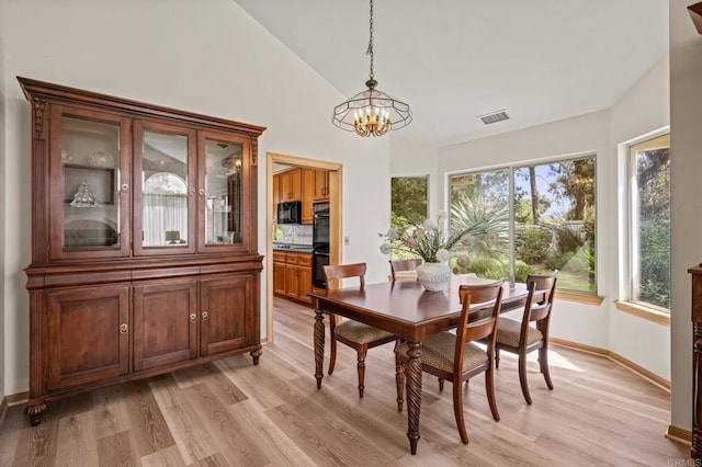 dining space featuring high vaulted ceiling, visible vents, light wood-style flooring, a chandelier, and baseboards