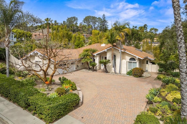 mediterranean / spanish-style home with a tiled roof, fence, and stucco siding