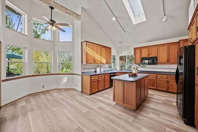 kitchen featuring dark countertops, black appliances, plenty of natural light, and a skylight