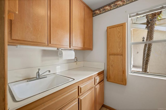 kitchen with brown cabinetry, light countertops, and a sink