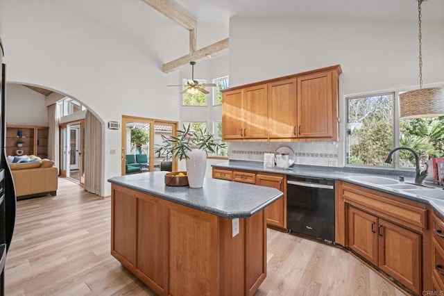 kitchen with arched walkways, a center island, dark countertops, a sink, and dishwasher