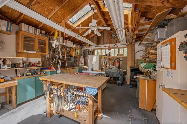 misc room featuring a skylight, unfinished concrete floors, a ceiling fan, and a workshop area