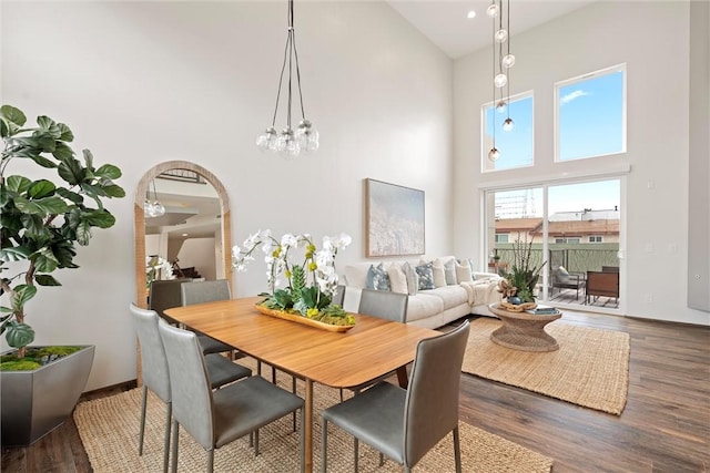 dining space with baseboards, a high ceiling, arched walkways, and wood finished floors