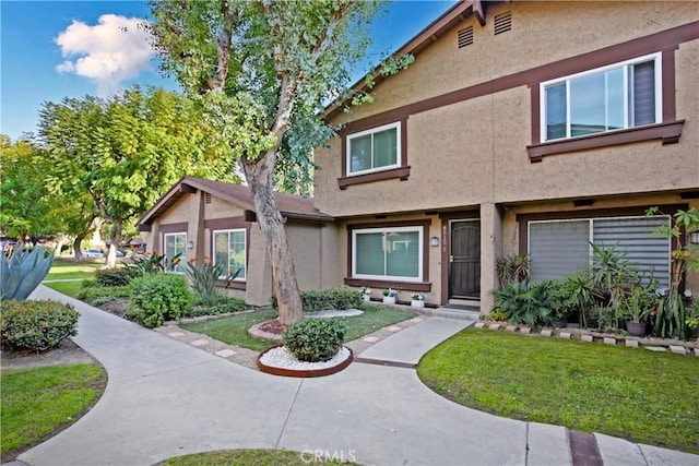 view of property with stucco siding and a front lawn