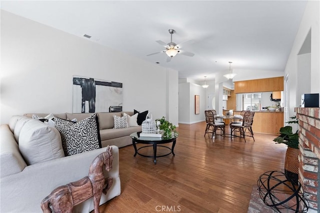 living area featuring lofted ceiling, wood-type flooring, visible vents, and a ceiling fan