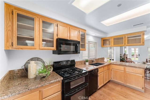 kitchen with a wealth of natural light, a sink, a peninsula, and black appliances