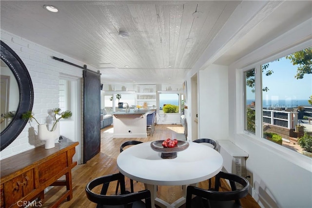 dining area featuring a barn door, wooden ceiling, recessed lighting, brick wall, and light wood-type flooring