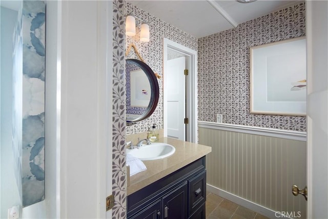 bathroom featuring a wainscoted wall, wallpapered walls, and vanity