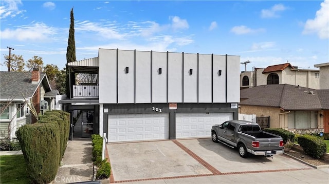 multi unit property with a garage, concrete driveway, and a balcony