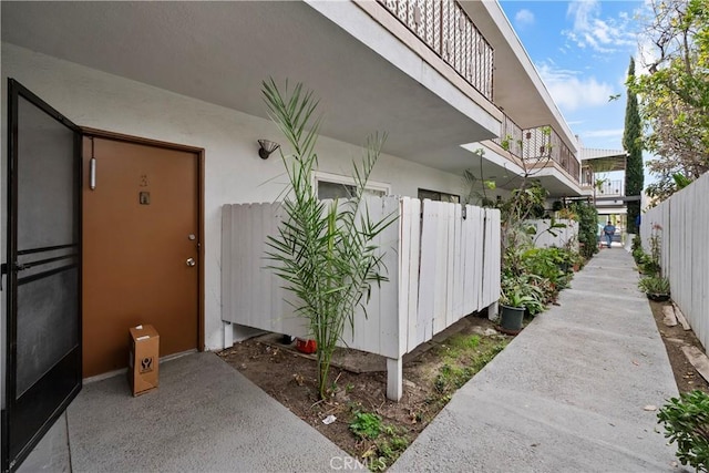 entrance to property with fence and stucco siding