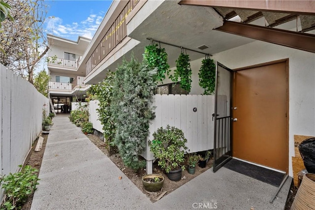 view of exterior entry with fence and stucco siding