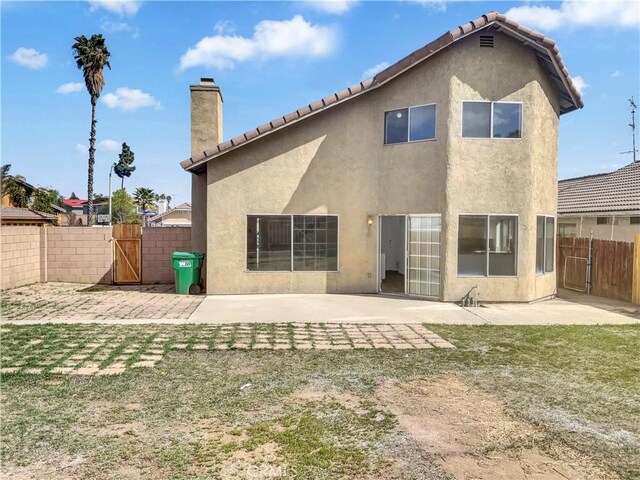 15279 Canyonstone Dr, Moreno Valley, CA 92551 - back of house featuring a chimney, a gate, fence, a patio, and stucco siding