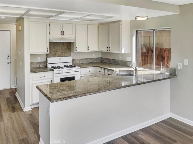 15279 Canyonstone Dr, Moreno Valley, CA 92551 - kitchen with dark wood finished floors, white gas stove, under cabinet range hood, a sink, and dark stone countertops