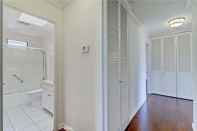 corridor with baseboards, visible vents, crown molding, and wood finished floors