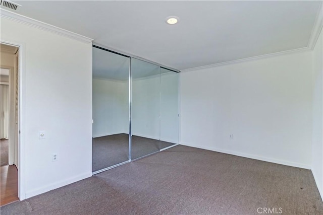 unfurnished bedroom with carpet, crown molding, a closet, visible vents, and baseboards