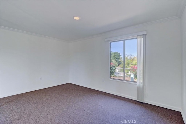 empty room with ornamental molding, dark colored carpet, and baseboards