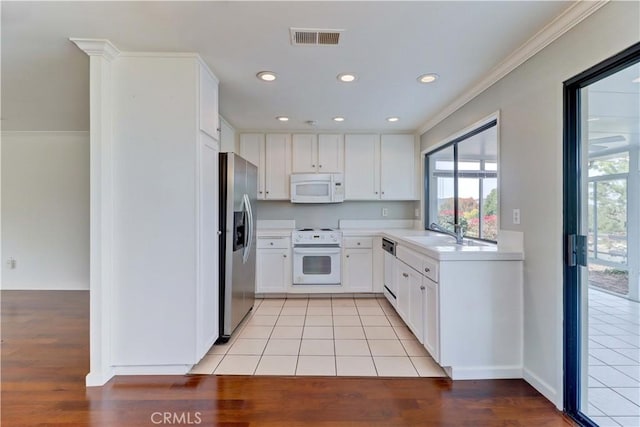 kitchen featuring white appliances, light tile patterned floors, visible vents, light countertops, and white cabinetry