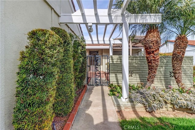 view of exterior entry with a gate, fence, and stucco siding