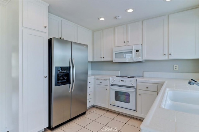 kitchen with light countertops, white appliances, and white cabinetry