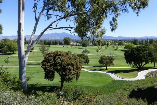 view of community featuring a mountain view, golf course view, and a lawn