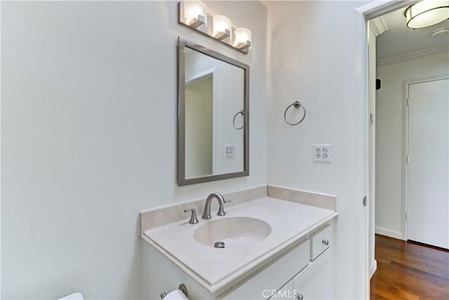 half bath with crown molding, wood finished floors, and vanity